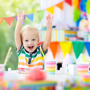  image of smiling little boy with his hands in the air surrounded by rainbow decorations 