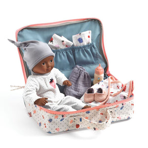 Doll in a travel bag with baby accessories on a white background