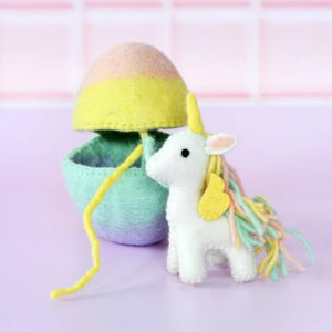 A colourful felt egg that is opening in the middle alongside a felt toy unicorn with pastel wool mane.