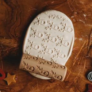 A bioplastic playdough rolling tool with reindeer pattern shown alongside light coloured playdough with the reindeer design imprinted.