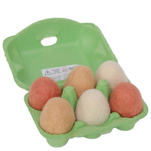 A green cardboard egg carton holding six felt wool felt eggs in peach, cream, and tan shades, isolated on a white background.