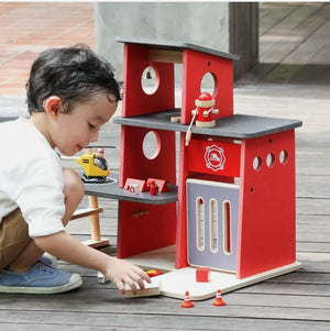 child playing with plantoys wooden fire station